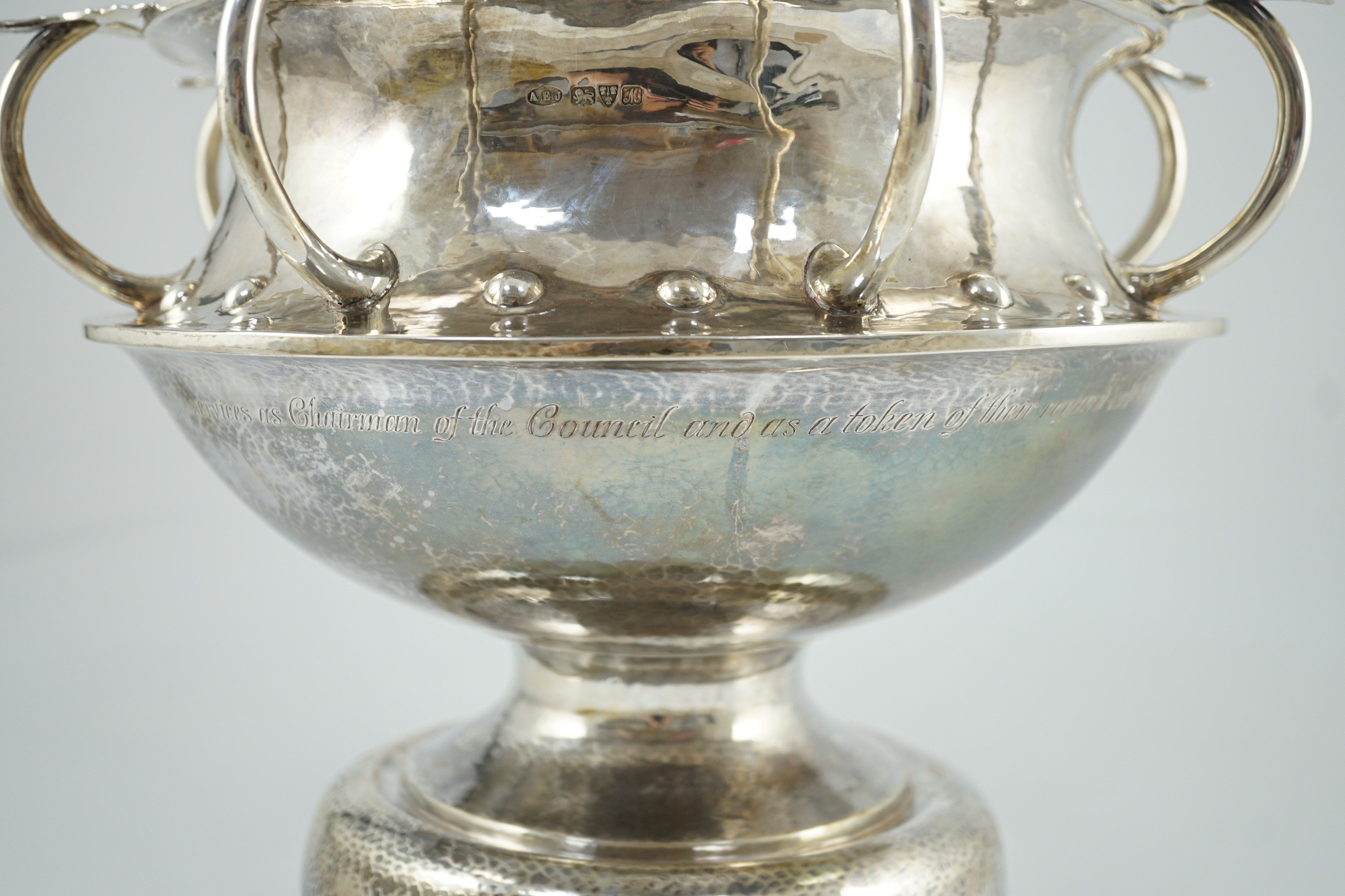 A George V Arts & Crafts planished silver octuple handled pedestal punch bowl, by Albert Edward Jones